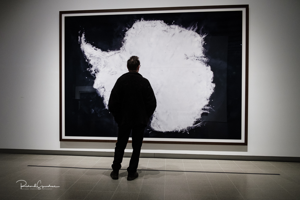 travel photography - travel photograher - colour image from a visit to the hayward gallery focusing on the visitors viewing the Gursky images in this image a visitor is stood in the front of a large image of white cloud shapes he seem to make a pleasing shape within the image