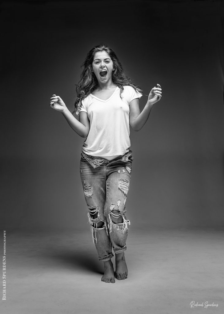 Fashion Photography - Fashion Photographer -model wearing torn jeans standing with one knew bent and arms slightly out to her sides