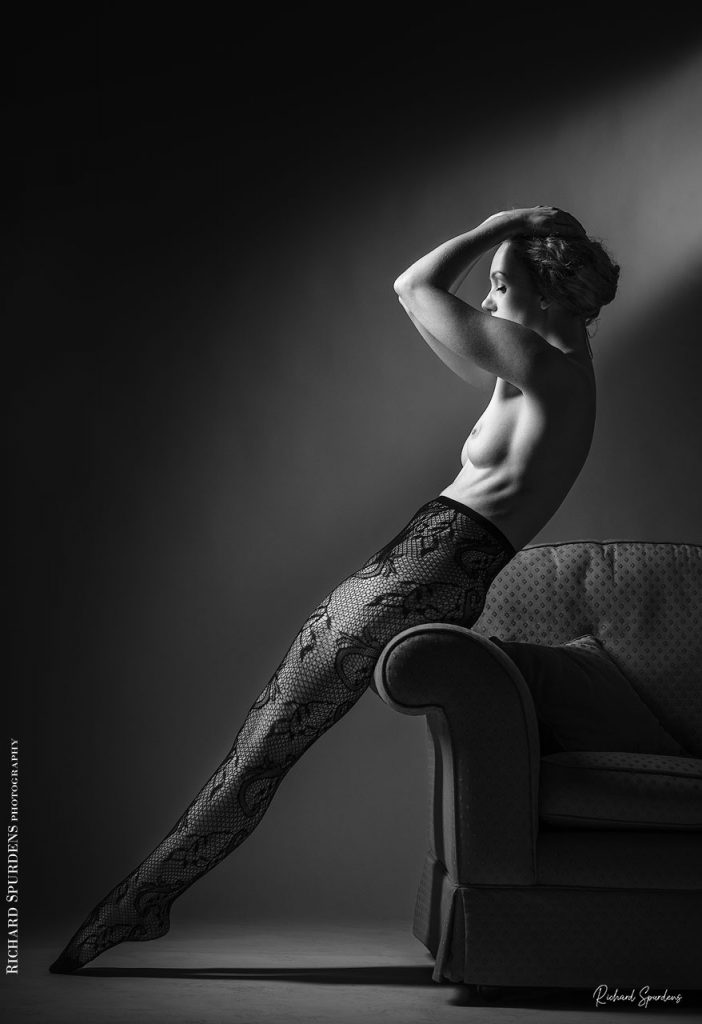 Fine Art Nude Photography - Nude Photography - Fine Art Nude Photographer - Ivory flame wearing paisley patterned tights and making strong female form shapes against the edge of a settee