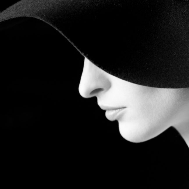 Portrait Photography - Portrait Photographer - monochorme profile image of the models face and hat making a curves shape