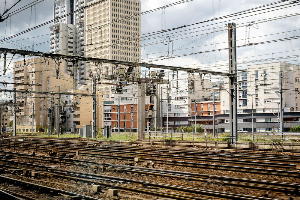 travel Photography - travel Photograher - railway lines overhead power lines for the trains and a background of vertical lines from the buildings make this a high and low line image - taken as the train leaves one of the paris stations