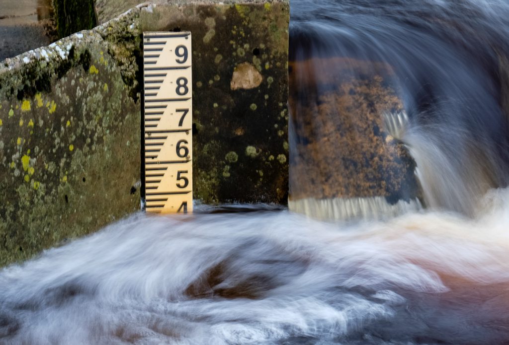 Landscape Photography - Landscape Photographer - colour image of the peat coloured water cascading past the river height marker