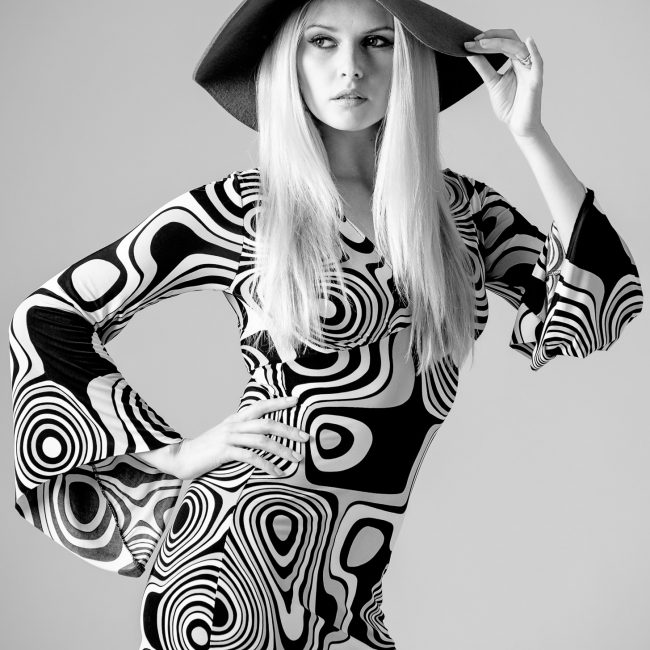 fashion photographer - fashion photography - monochrome vintage fashion shoot with model wear a sixty style psychedelic designed dress hat and black shoes