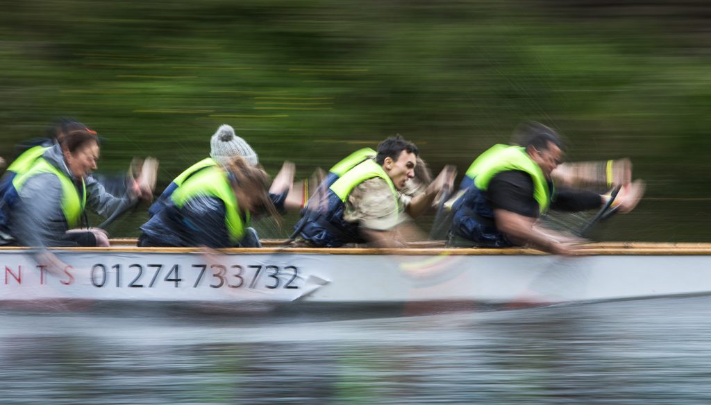 sport photography - sport photographer -colour image of dragon boat racing on the river aire at roberts park saltaire, slow shutter speed was used to give an feel of the speed the boat is traveling