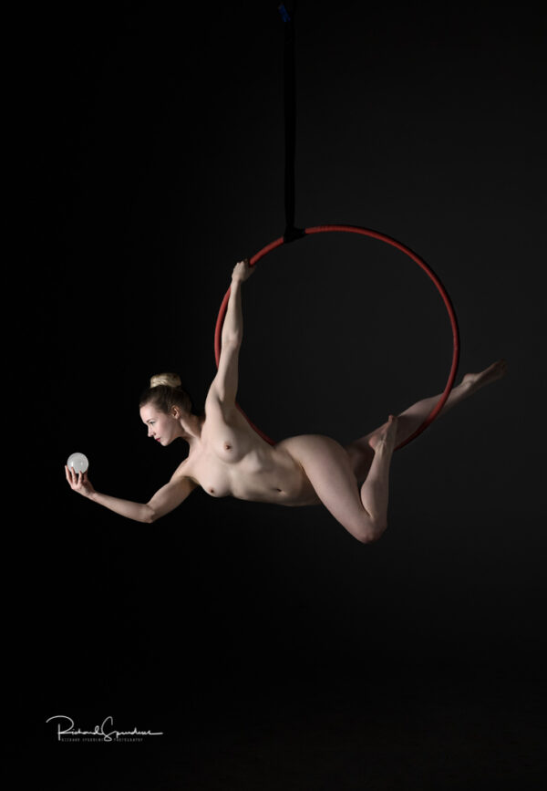 Aerial Arts photographer - Aerial hoop photographer - Aerial Arts photography - aerial artist using a red aerial hoop to hold a dynamic pose at the bottom of the hoop