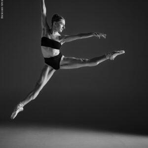 Dance Photographer - monochrome image of dancer leaping in a star jump towards the light