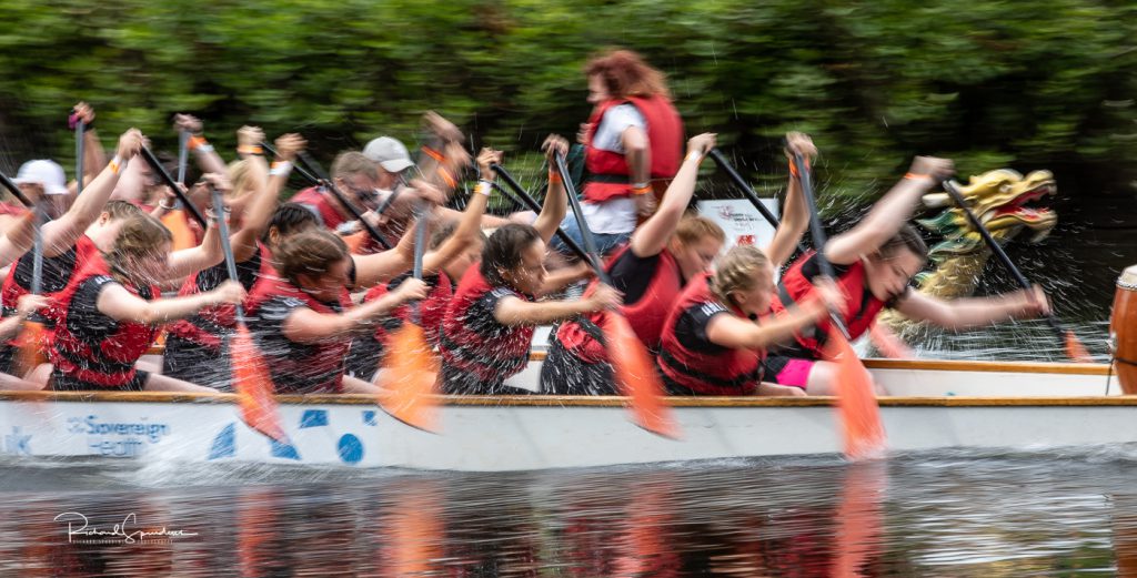 sport photography - sport photographer -colour image of dragon boat racing on the river aire at roberts park saltaire, slow shutter speed was used to give an abstract effect with a flash firing to captured the water spray droplets