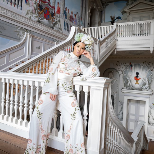 Fashion Photography - Fashion Photographer - an interior shot of the model wearing a white trouser suit and floral head piece in the white stair way