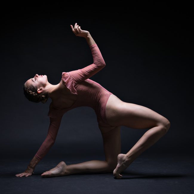 Dance Photographer - Dance photography - a colour image of dancer alya rose with bent legs and leaning back on her left arm with her right reaching up towards the light