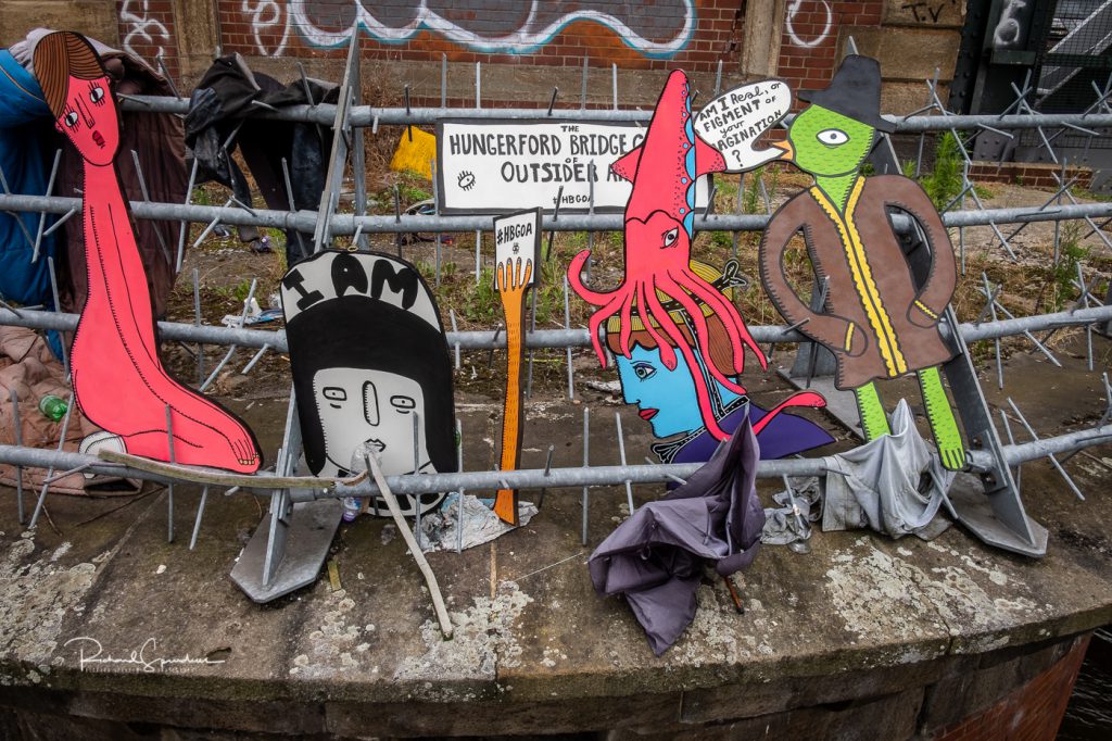 street photography - street photographer - hungerford footbridge there is some interesting art instalation on the supporting pillar for the railway bridge