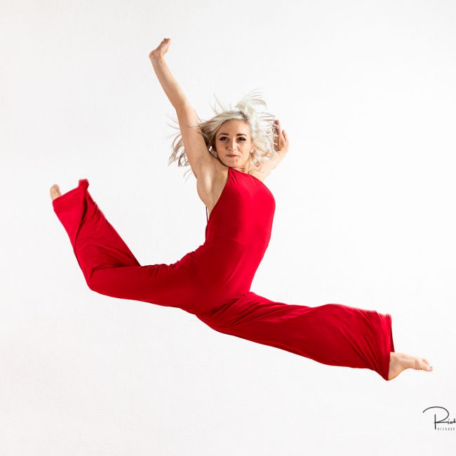 Dance Photographer - Dance photography - colour image of a dancer in a freeform leap wearing a red jump suit