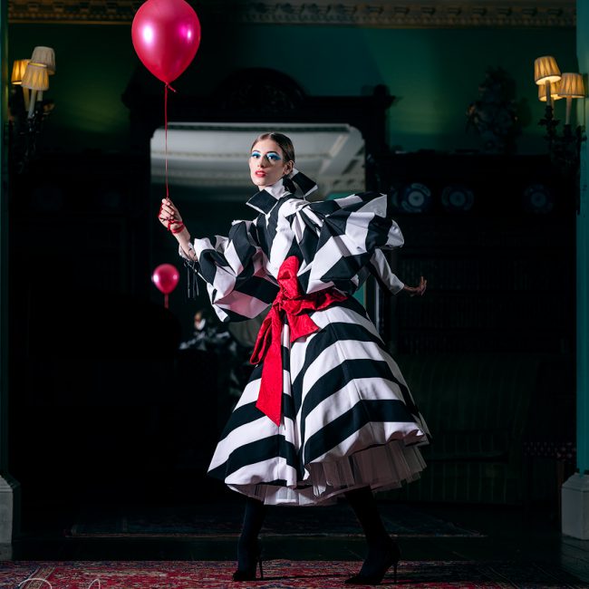 Fashion photographer - Fashion photography - fashion shoot the model is wearing a black and white dress with a red shash and holding the red balloon