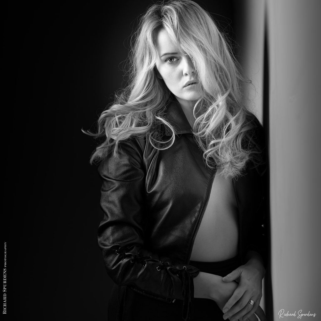 Fashion Photography - Fashion Photographer - model in her leather jacket with a single eye looking into the camera