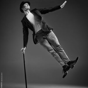 Dance Photographer - Dance photography - monochrome image featureing dancer hamish using a cane to jump into the air and hold a charile chaplin pose