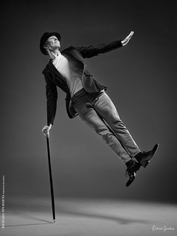 Dance Photographer - Dance photography - monochrome image featureing dancer hamish using a cane to jump into the air and hold a charile chaplin pose