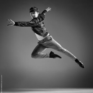 Dance Photographer - Dance photography - male dancer making a leap across the image wearing a leather jacket and cap based on a west side story idea