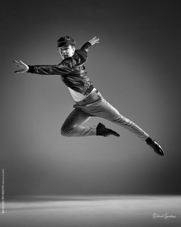 Dance Photographer - Dance photography - male dancer making a leap across the image wearing a leather jacket and cap based on a west side story idea