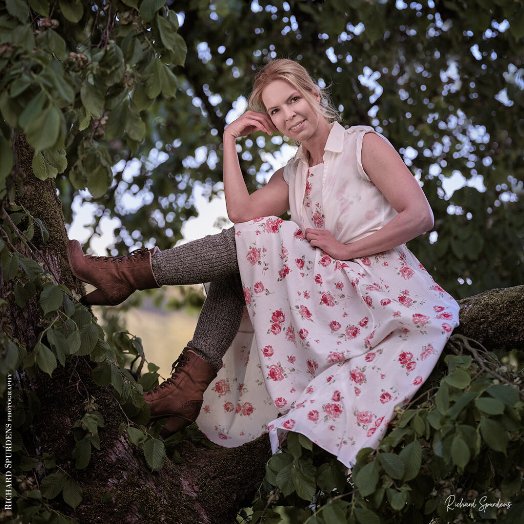 dance photographer - dance photography - outdoor dancer seated in a large tree in a white dress with red flowers patterns