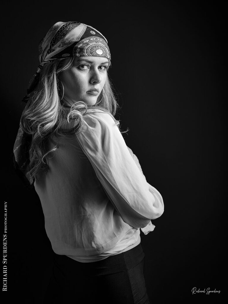 fashion photography fashion photographer - monochrome image of model wearing a white blouse and patterned bandana looking over her shoulder back to the camera