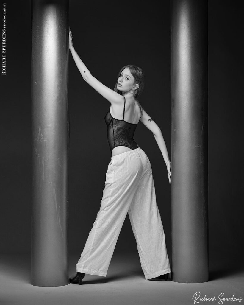 fashion photography, fashion photographer model wearing linen summer trousers and black body topstanding between two pillars