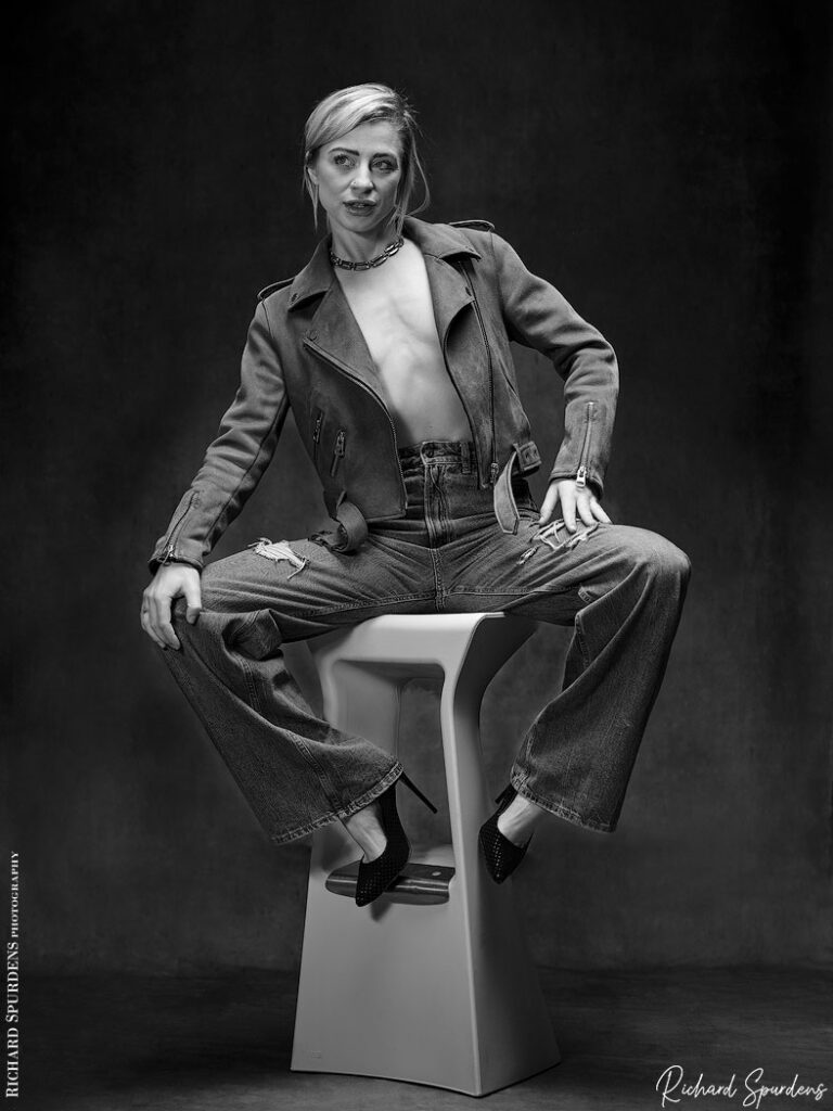 fashion photography - fashion photographer - Crystal fashion fun model wearing leather jacket and torn jeans posing on white stool